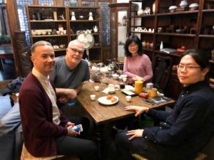 Four people seated around a table sampling specialty tea.