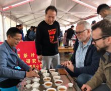 Liu Guo Ying, left, brewing specialty tea at a tea table surrounded by tasters for the Zhu Xi Cup tea competition.
