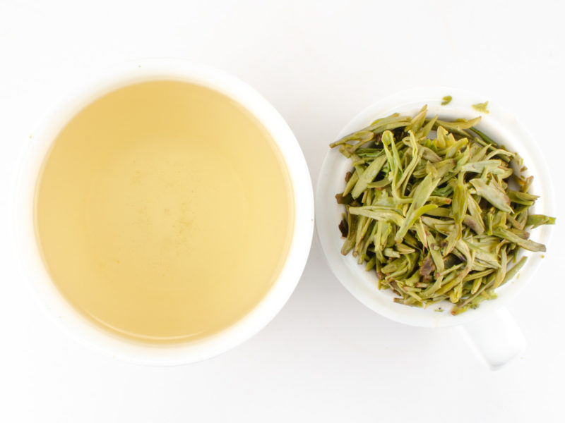 Cupped infusion of Da Fo Longjing (Big Buddha Dragon Well) green tea and strained leaves.