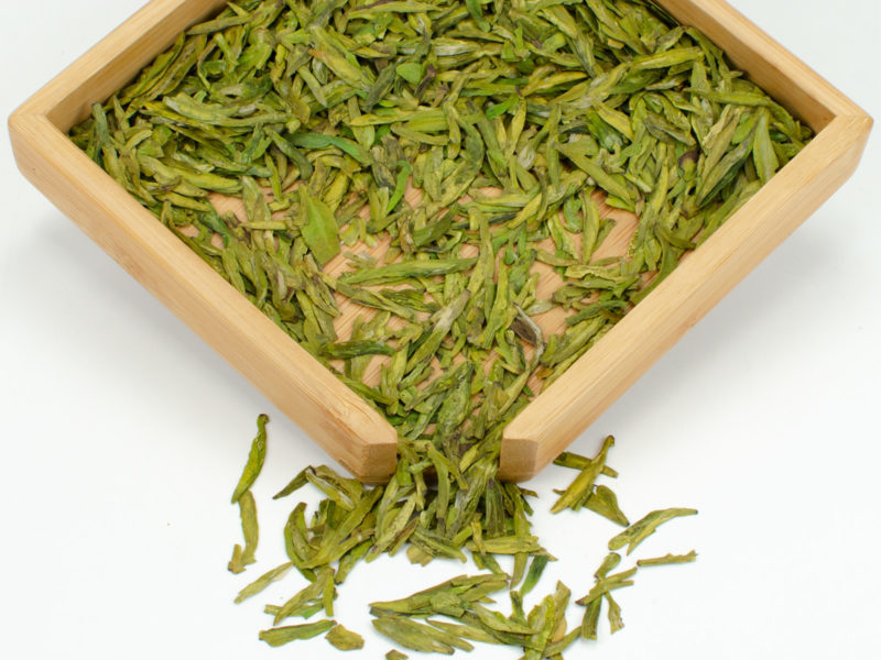 Shifeng Longjing (Shifeng Dragon Well) Green tea dry leaves in a wooden display box.
