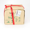 The traditional brown paper packaging that Shifeng Longjing Dragon Well Green Tea from West Lake comes in: s small paper bundle with metallic green detailing tied up with a red ribbon, with a lot sticker on the outside.