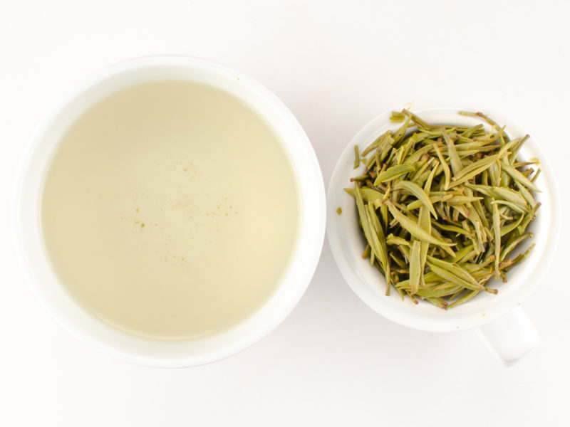 Cupped infusion of Junshan Yinzhen yellow tea and strained leaves.