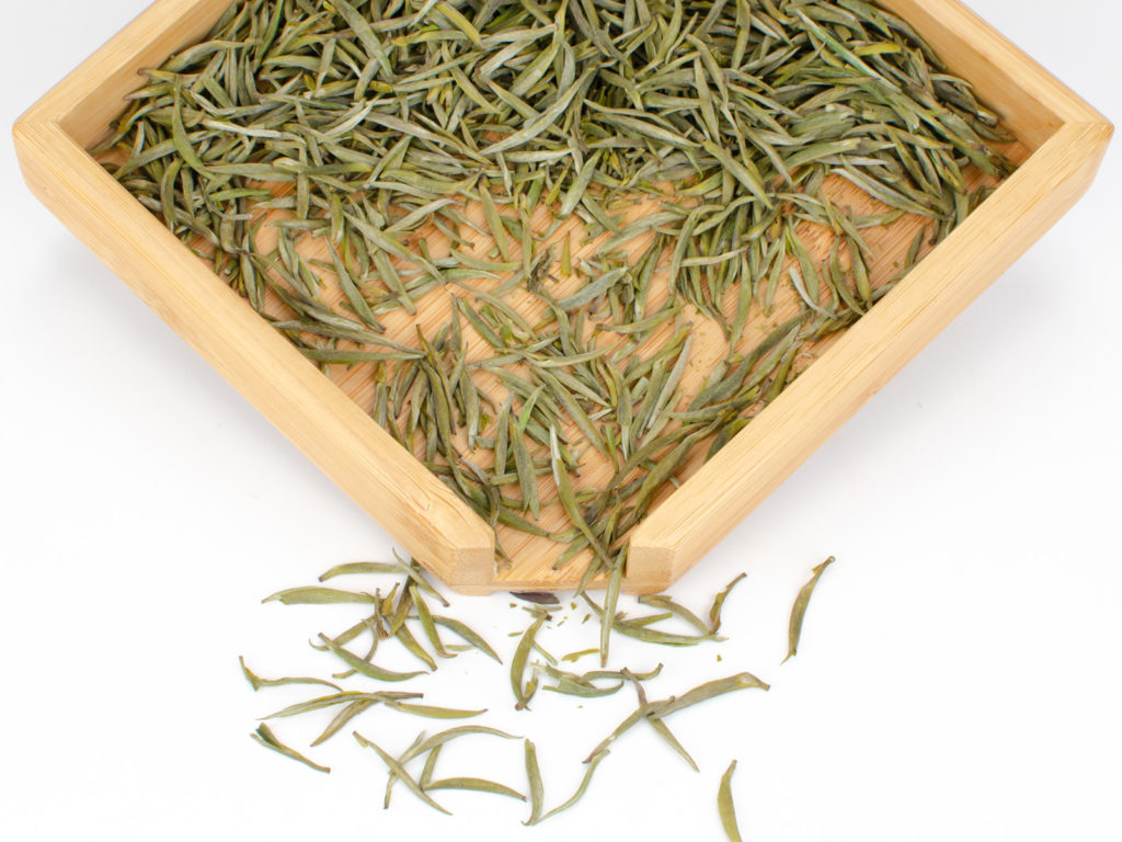 Junshan Yinzhen dry yellow tea leaves displayed on a bamboo tray.