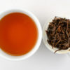 Cupped infusion of Laoshu Dianhong (Old Tree Yunnan) tea and strained leaves.