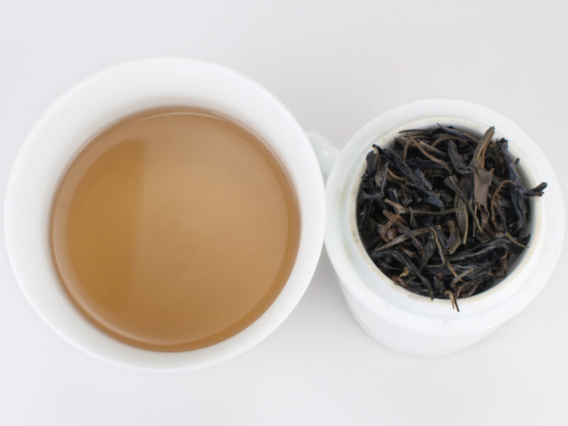 Cupped infusion of Zijuan Chuncha (Purple Spring Tea) sheng puer tea and strained leaves.