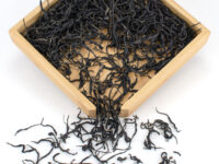 Zijuan Chuncha (Purple Spring Tea) sheng puer tea leaves in a wooden display box.