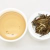 Bai Long Xu (White Dragon Whiskers) wet tea leaves next to a cup of the infused tea