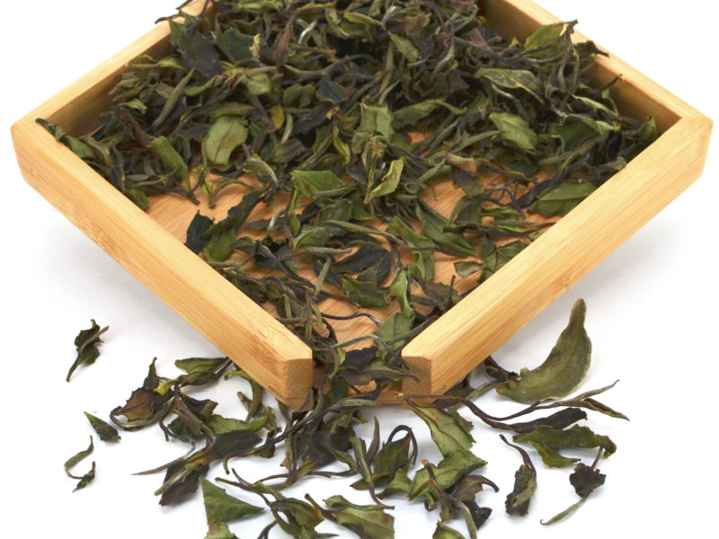 Tieguanyin Baicha white tea dry leaves in a wooden display box.