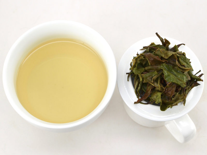 Cupped infusion of Tieguanyin Baicha white tea and strained leaves.