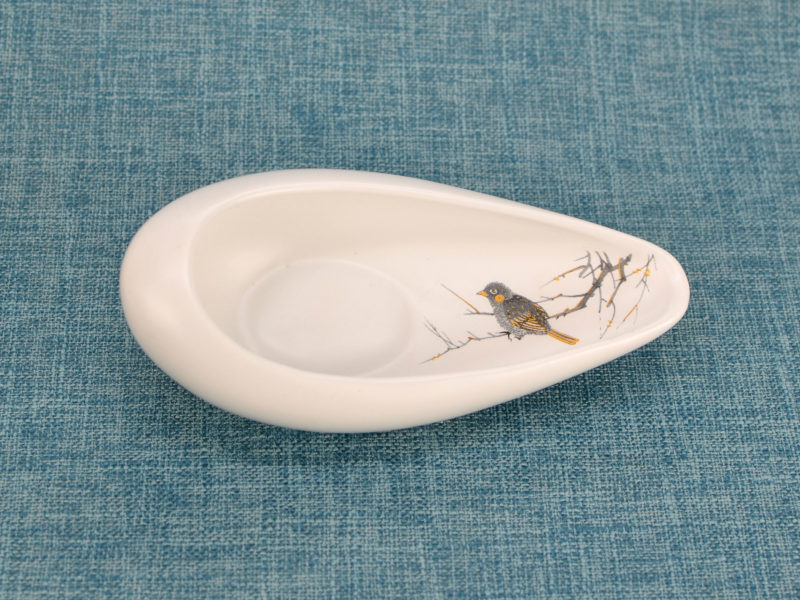 Above view of matte white porcelain display plate with bird.