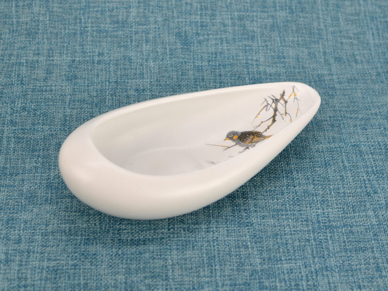 Angle view of matte white porcelain display plate with bird.