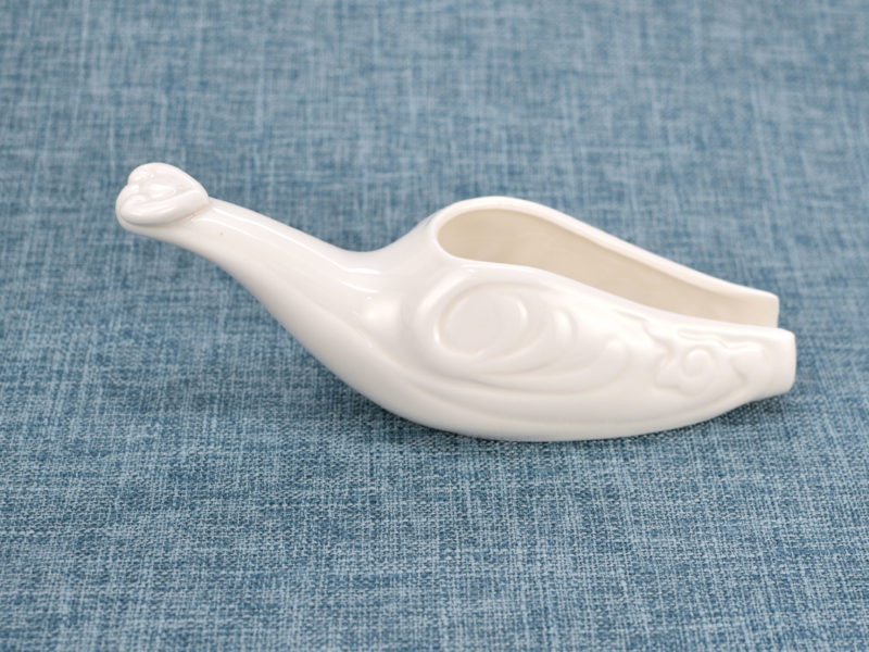 Side view of white porcelain tea spoon.