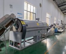 A large cylindrical rolling oven in a bright, clean factory room.