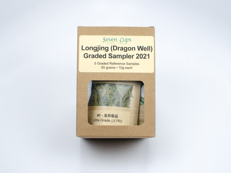 The simple brown paper gift box for the Longjing (Dragon Well) Graded Green Tea Sampler, with the packets of tea inside visible through a small clear window.
