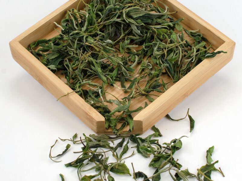 Mountain Forest Huangshan Maofeng green tea dry leaves in a wooden display box.