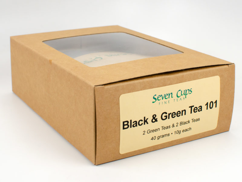 The simple brown paper gift box for the Black & Green Tea 101 sampler, with the packets of tea inside partly visible through a small clear window.