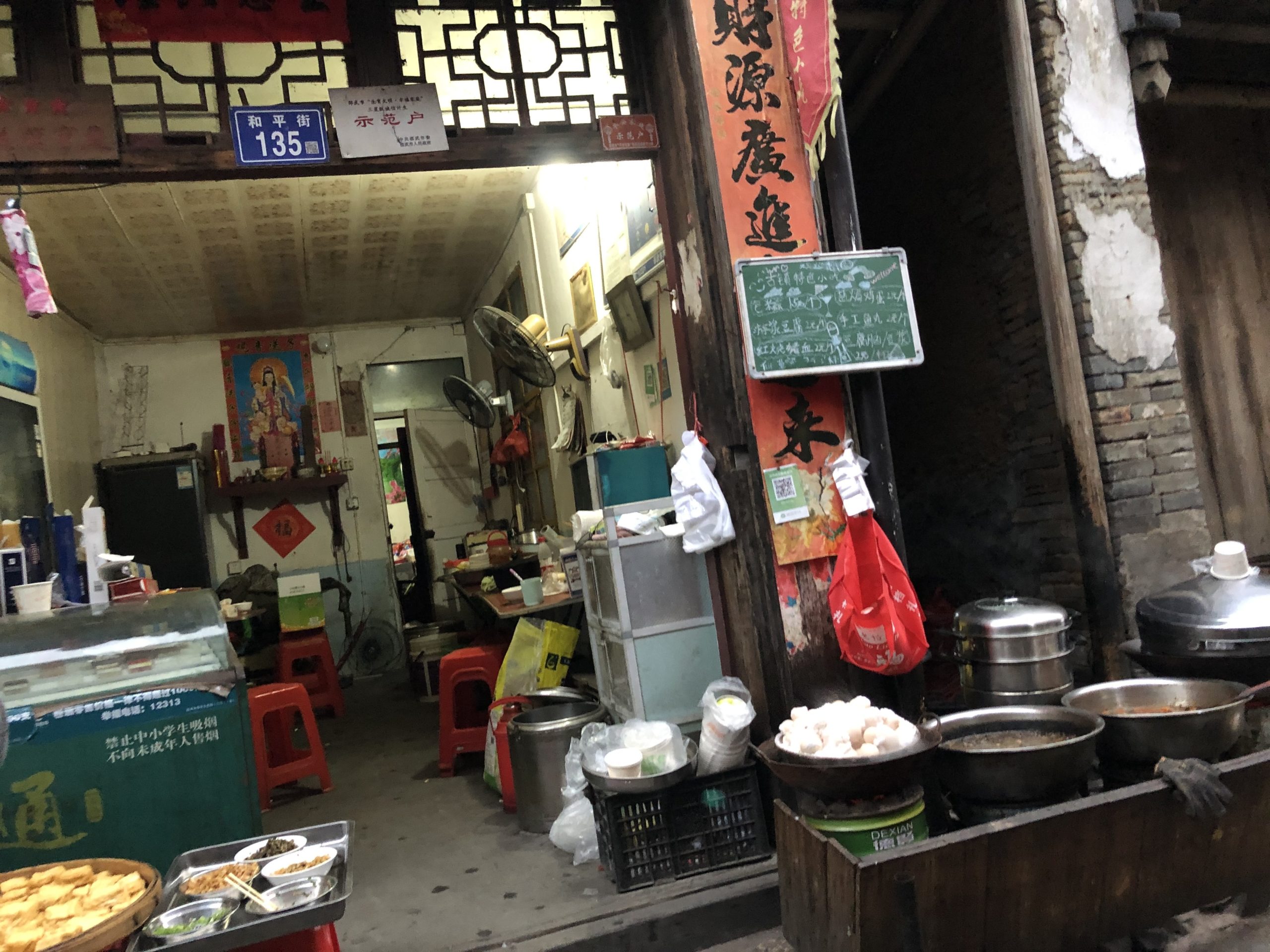 Looking into the tiny cluttered kitchen of a streetside tofu restaurant.