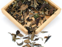 Yue Guang Bai (White Moonlight) dry white puer tea leaves displayed on a bamboo tray.