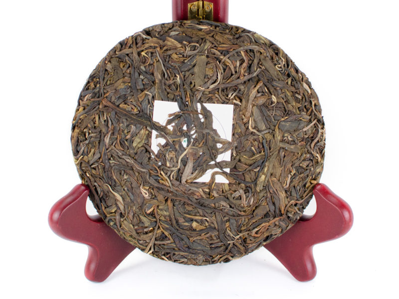 Unwrapped Xiaohuzhai 2019 sheng puer cake in a stand to show off leaves.