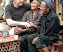 Three people sitting on a bench laughing.