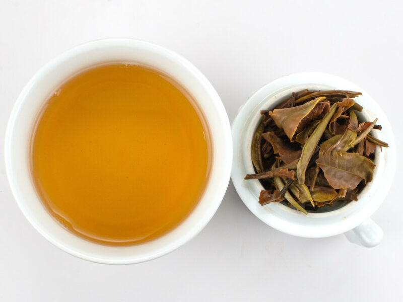 Cupped infusion of Yue Guang Bai (White Moonlight) Yunnan white tea and strained leaves.