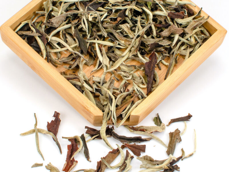 Yue Guang Bai (White Moonlight) dry Yunnan white tea leaves displayed on a bamboo tray.