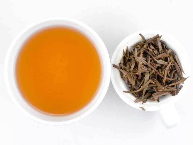 Cupped infusion of Zi Ya (Purple Buds) sheng puer tea and strained leaves.
