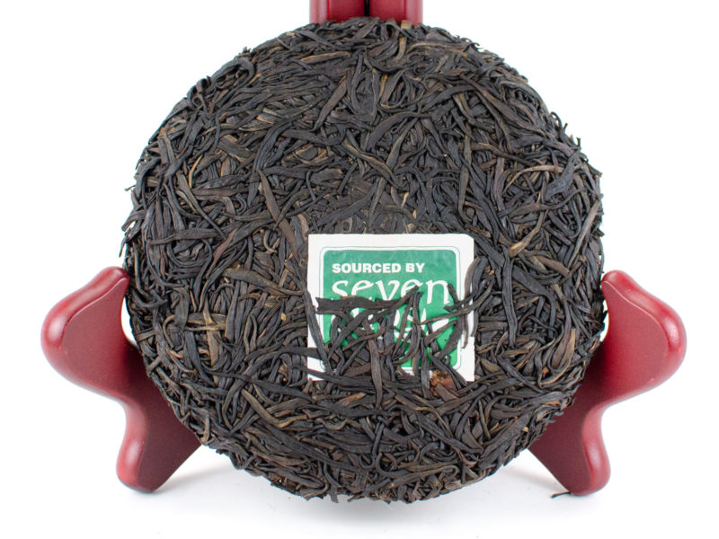 Unwrapped Zi Ya (Purple Buds) 2021 sheng puer cake in a stand to show off leaves.