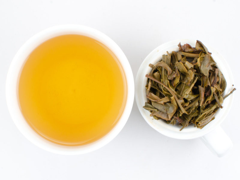 Cupped infusion of Xinbanzhang sheng puer tea and strained leaves.
