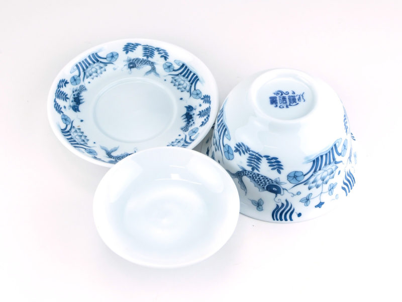 A Blue and White Fish Gaiwan disassembled and viewed from above to show the pattern on the saucer and bowl and the plain inside of the lid.