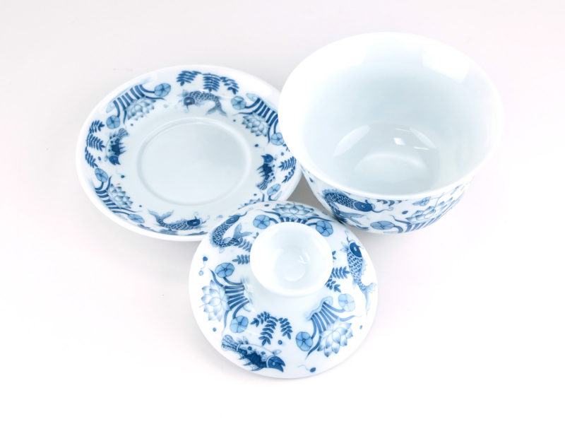 A Blue and White Fish Gaiwan disassembled and viewed from above to show the pattern on the saucer and lid and the plain inside of the bowl.