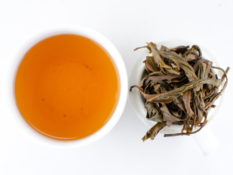 Cupped infusion of Laowushan (Laowu Mountain) sheng puer tea and strained leaves.