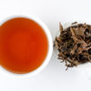 Cupped infusion of Jingmaishan (Jingmai Mountain) sheng puer tea and strained leaves.