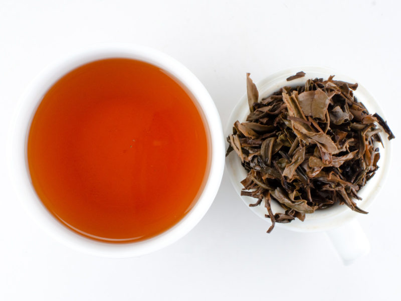 Cupped infusion of Jingmaishan (Jingmai Mountain) sheng puer tea and strained leaves.