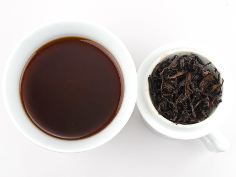 Cupped infusion of Muzhi Xiang (Sweet Timber) shu puer tea and strained leaves.