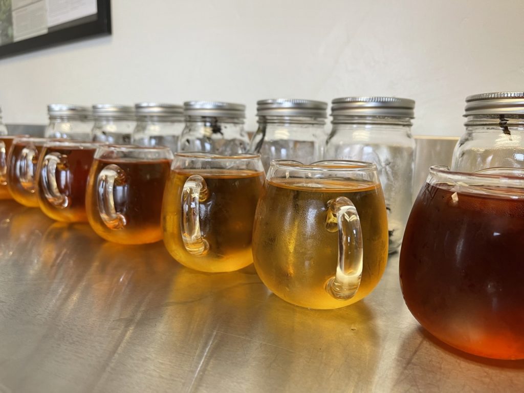 A lineup of glass pitchers filled with cold brew black tea.