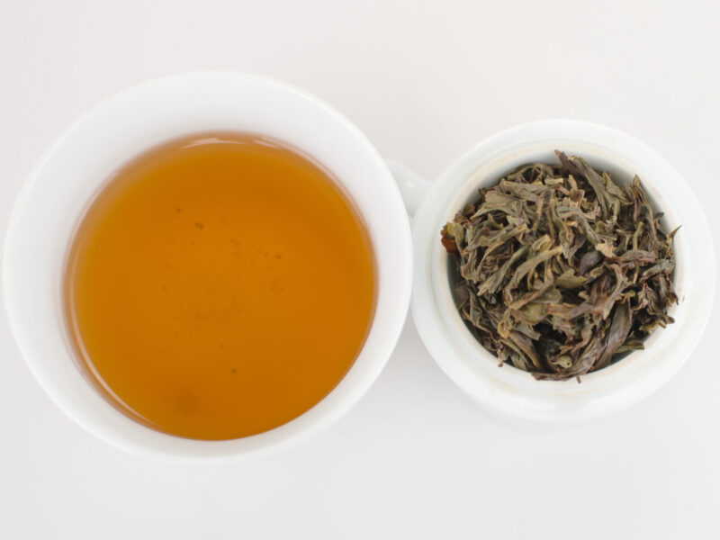 Cupped infusion of Jianghua Xiang (Ginger Flower) Dan Cong wulong tea and strained leaves.