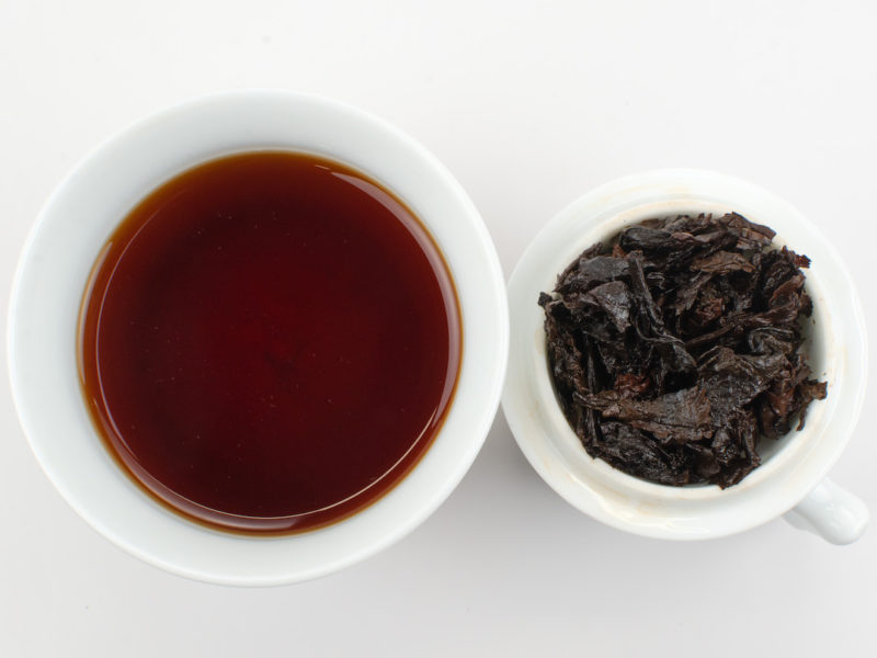 Cupped infusion of Huangjin Suiyue (Golden Age) shu puer tea and strained leaves.