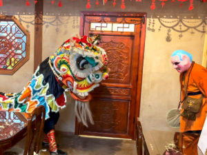 A colorful dancing lion being led through the teahouse to bless it.