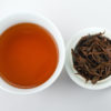 Cupped infusion of Zhongguo Hong (China Red) black tea and strained leaves.