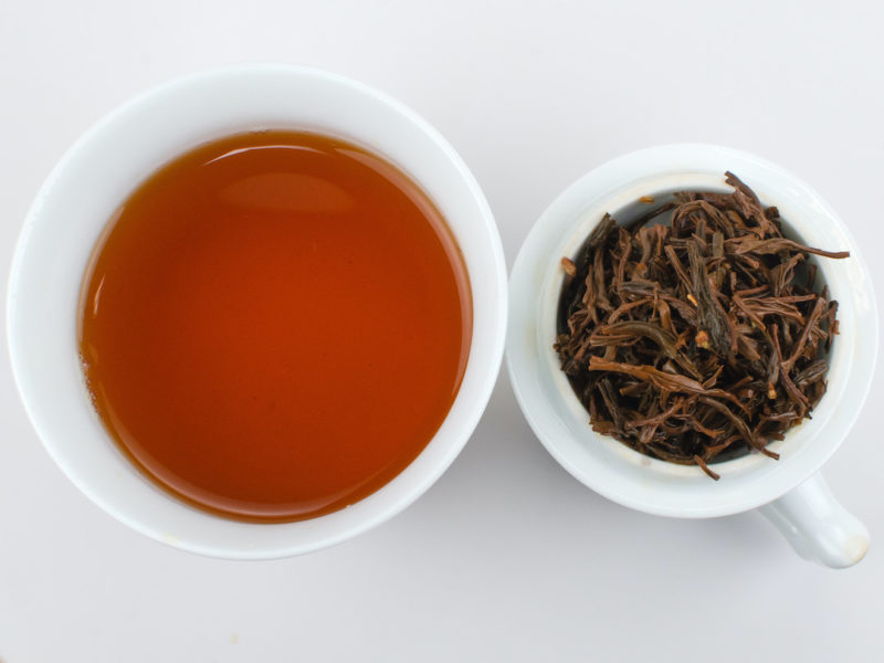 Cupped infusion of Gui Hua Qimen (Osmanthus Keemun) black tea and strained leaves.