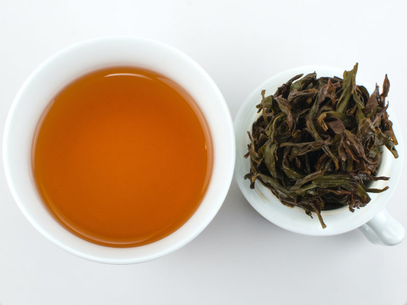Cupped infusion of Qi Dan Maocha rock wulong tea and strained leaves.