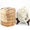 A tong of stacked Bai Long Xu (White Dragon Whiskers) white puer cakes wrapped in bamboo.