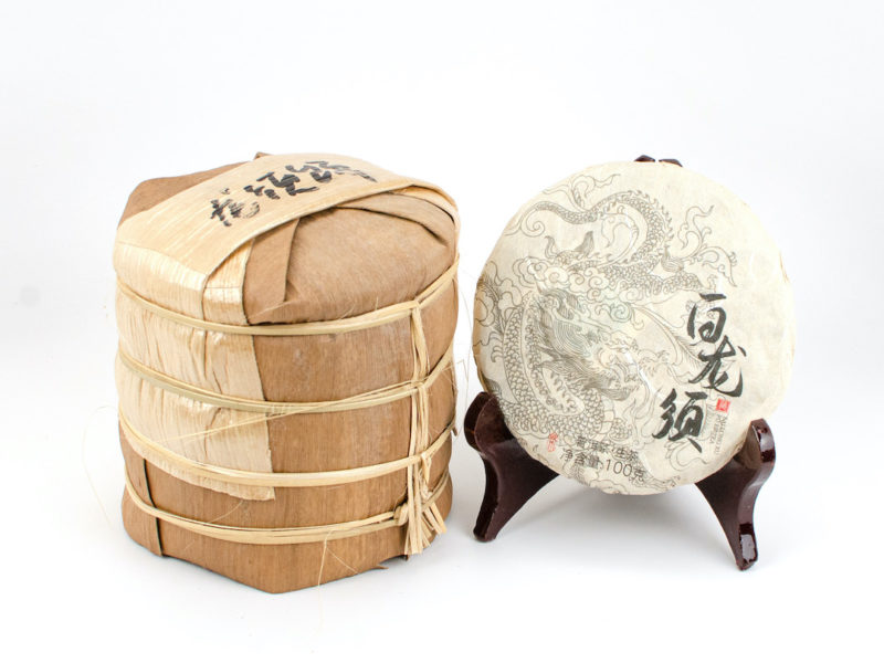 A tong of stacked Bai Long Xu (White Dragon Whiskers) white puer cakes wrapped in bamboo.