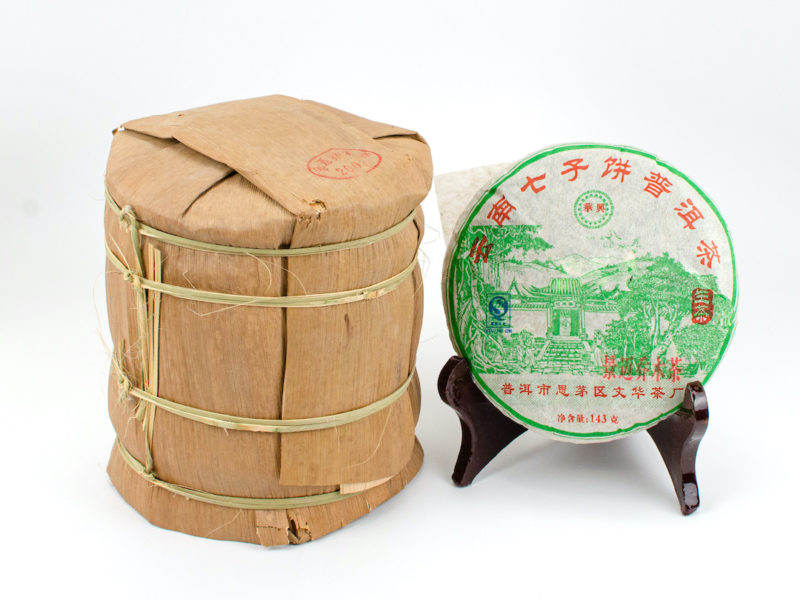 A tong of stacked Jingmaishan (Jingmai Mountain) sheng puer cakes wrapped in bamboo.