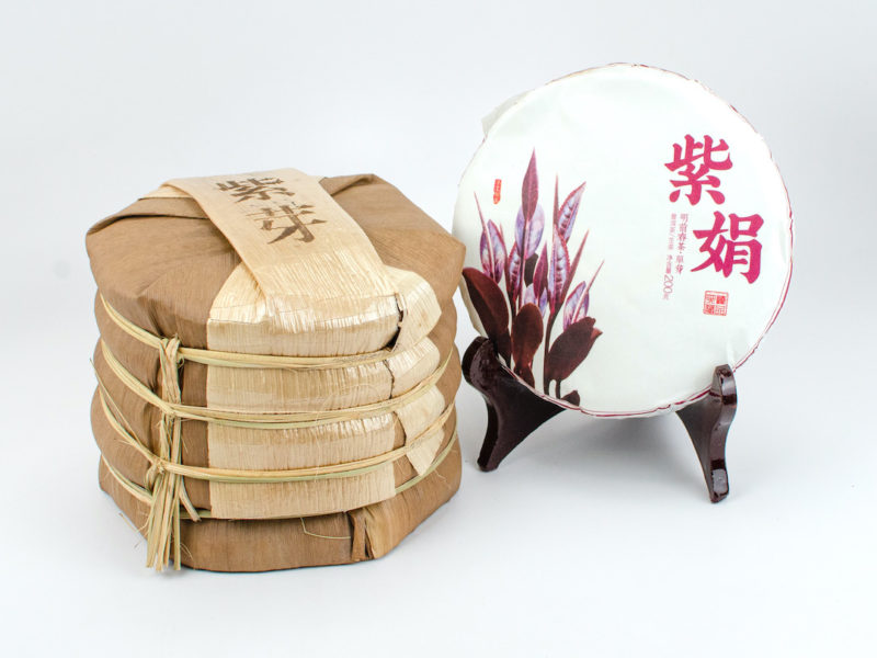 A tong of stacked Zi Ya (Purple Buds) sheng puer cakes wrapped in bamboo.