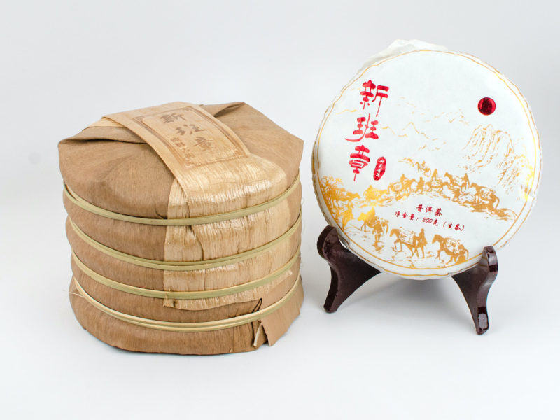 A tong of stacked Xinbanzhang sheng puer cakes wrapped in bamboo.