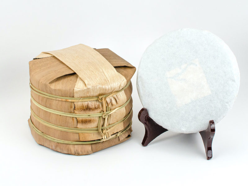 A tong of stacked Youle Huangshancha (Youle Forest Tea) sheng puer cakes wrapped in bamboo.