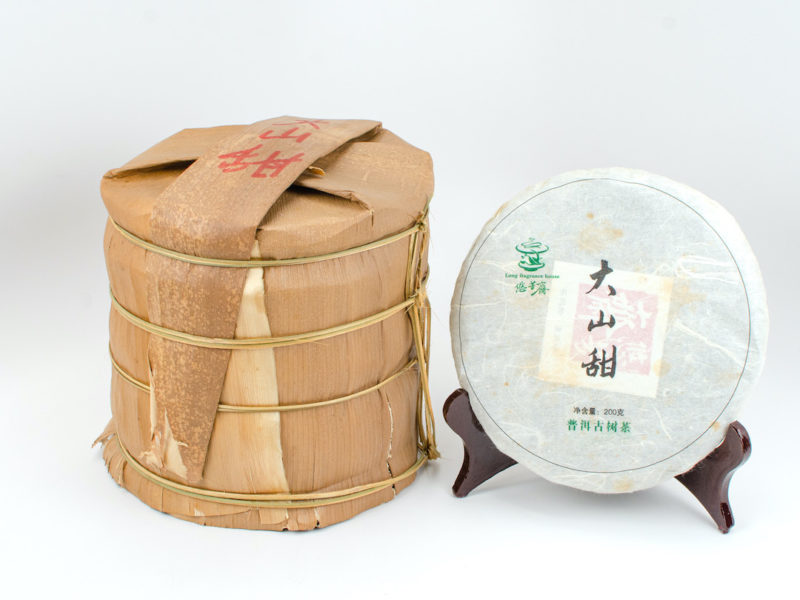A tong of stacked Da Shan Tian (Sweet Mountain) sheng puer cakes wrapped in bamboo.