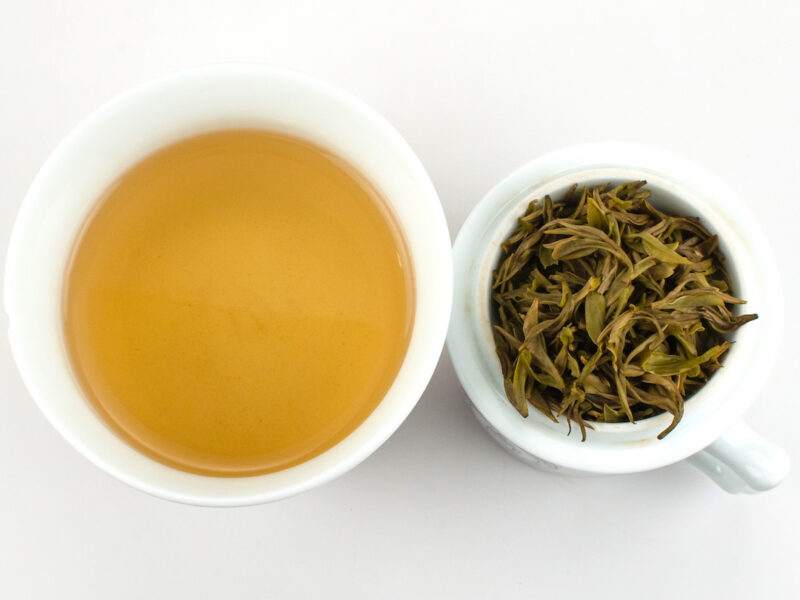 Cupped infusion of Early Spring Mogan Yellow tea and strained leaves.